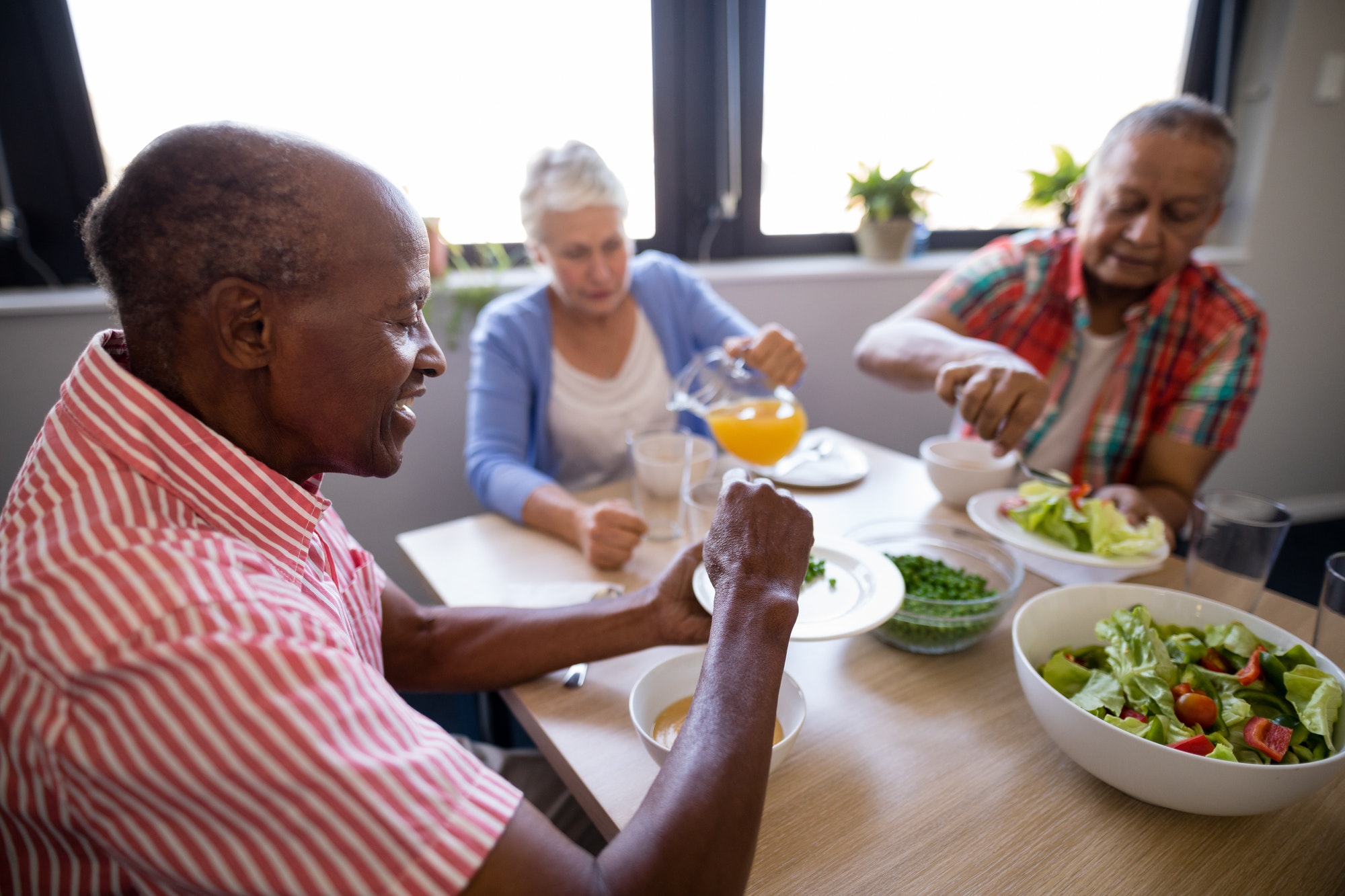 Senior people having juice and salad at table